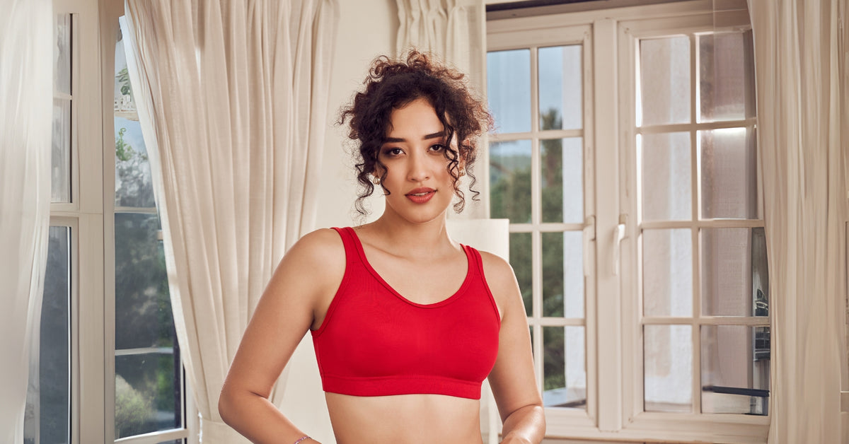 A woman in a red full-coverage bra by a window